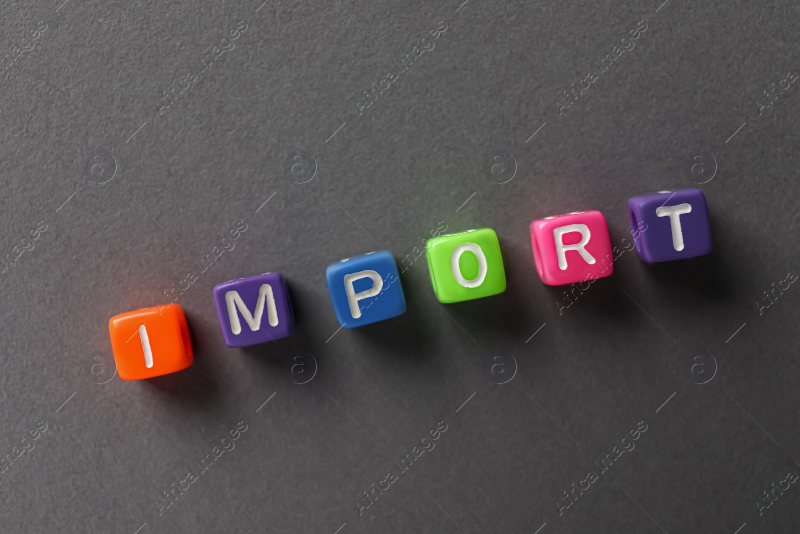 Photo of Word Import made of colorful cubes on dark grey background, flat lay