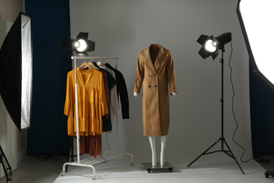 Ghost mannequin, clothes and professional lighting equipment in modern photo studio