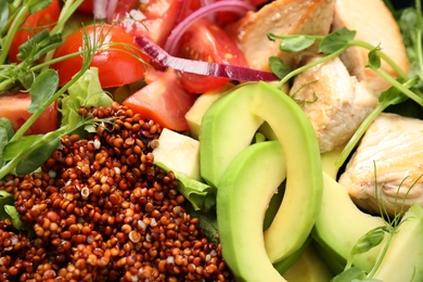 Photo of Delicious avocado salad with quinoa as background, closeup