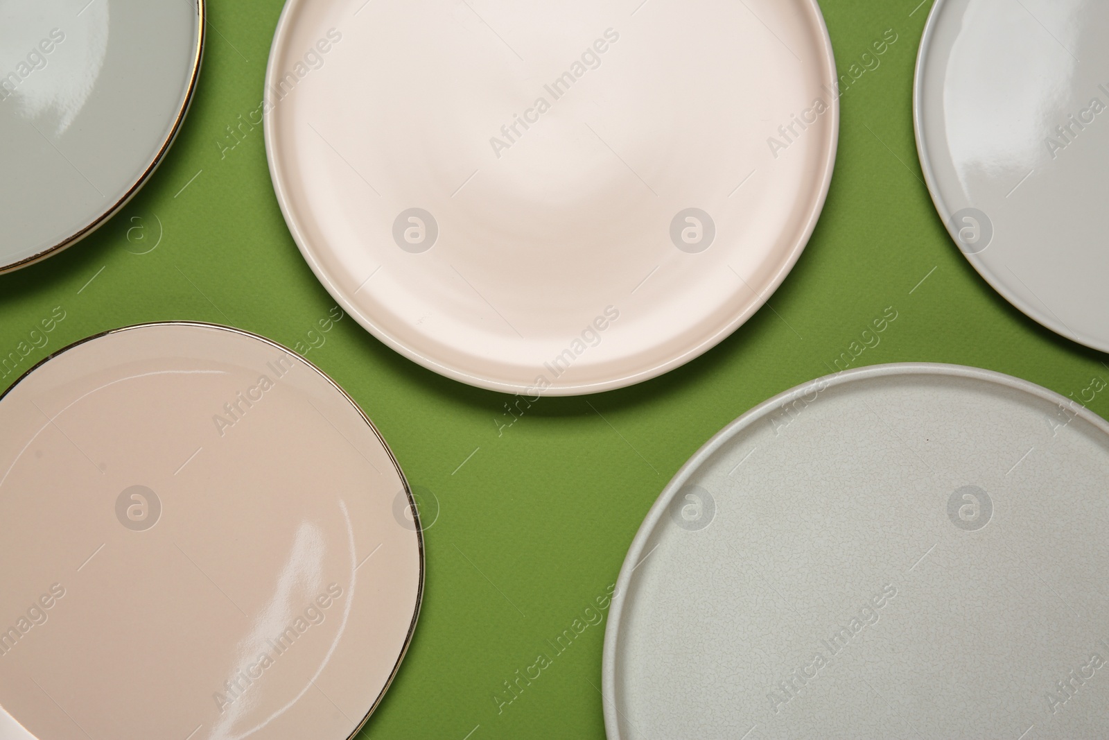 Photo of Beautiful ceramic plates on green background, top view