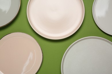 Photo of Beautiful ceramic plates on green background, top view