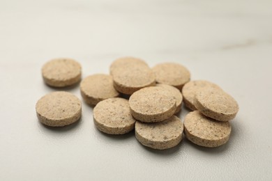 Photo of Dietary supplement pills on white table, closeup