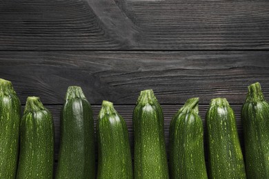 Photo of Raw ripe zucchinis on black wooden table, flat lay. Space for text