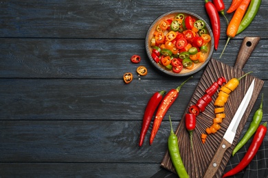 Flat lay composition with different hot chili peppers on grey wooden table. Space for text