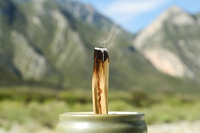 Photo of Burning palo santo stick in high mountains, closeup