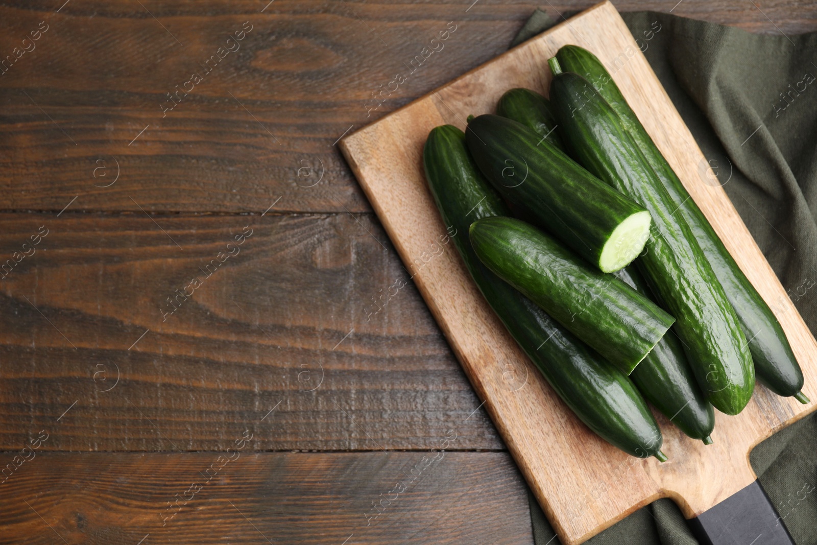 Photo of Fresh cucumbers on wooden table, top view. Space for text