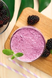 Photo of Delicious blackberry smoothie in glass and berries on wooden table, flat lay