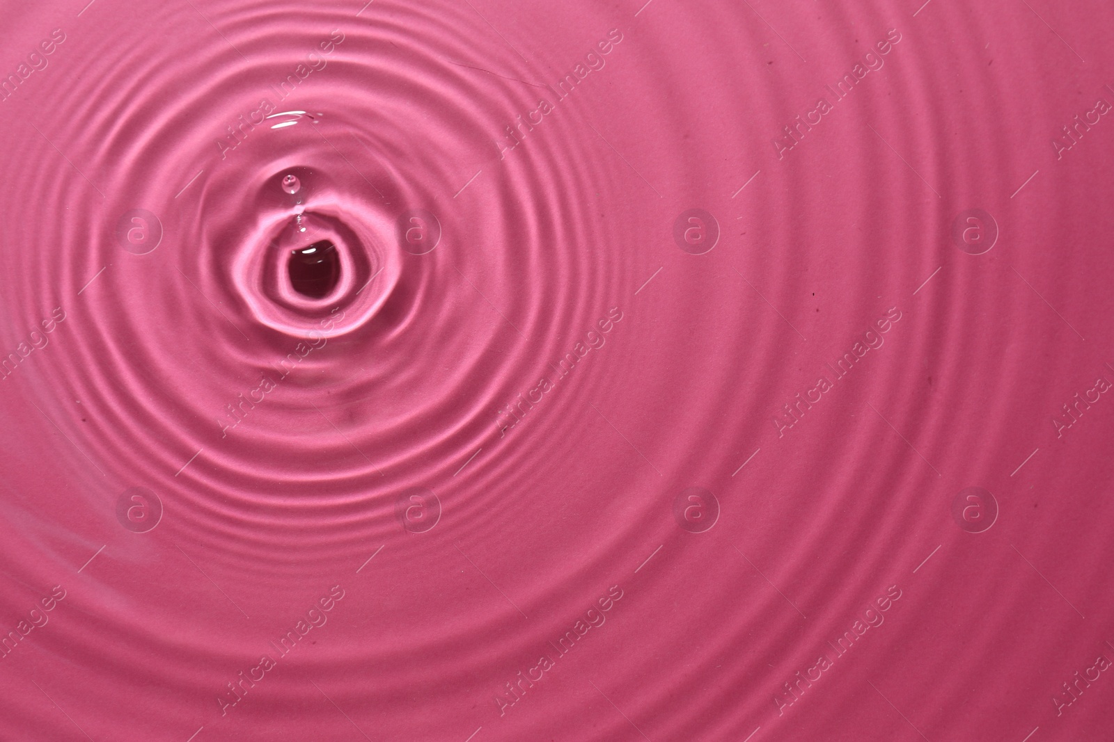 Photo of Rippled surface of clear water on bright pink background, top view