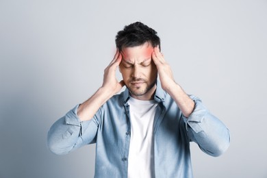 Image of Man suffering from terrible migraine on light grey background