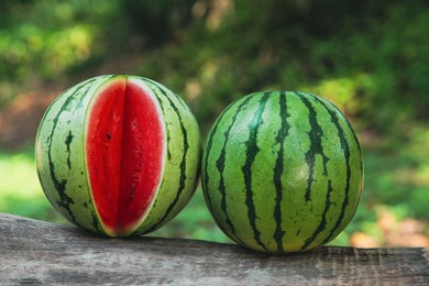 Photo of Delicious whole and cut watermelons on log outdoors