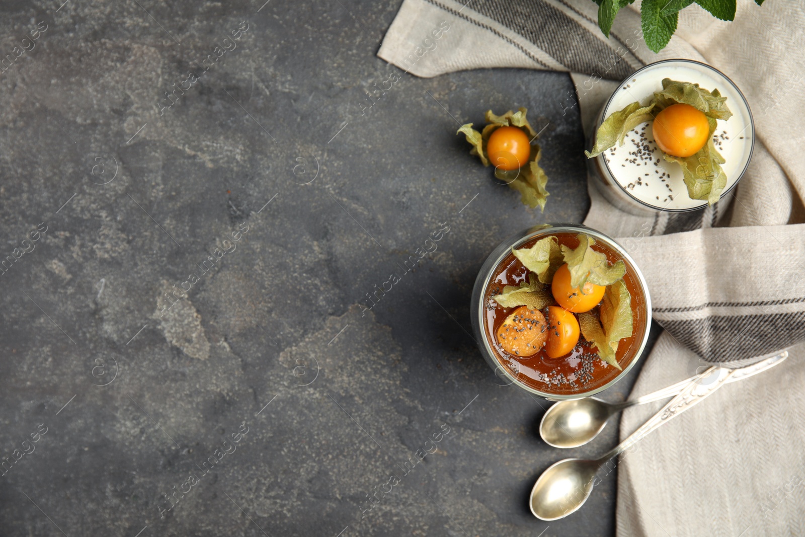 Photo of Delicious desserts decorated with physalis on grey table, flat lay. Space for text