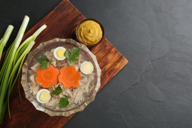 Delicious aspic with meat served on black slate table, flat lay. Space for text