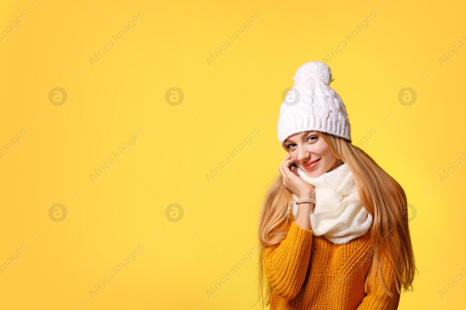 Photo of Portrait of emotional young woman in stylish hat, sweater and scarf on color background, space for text. Winter atmosphere