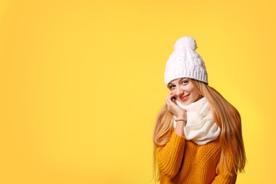 Portrait of emotional young woman in stylish hat, sweater and scarf on color background, space for text. Winter atmosphere