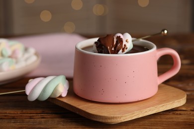 Cup of delicious hot chocolate and marshmallows on wooden table, closeup
