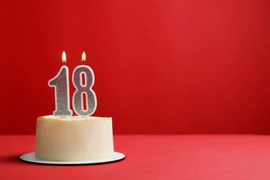 Photo of Coming of age party - 18th birthday. Delicious cake with number shaped candles on red background, space for text