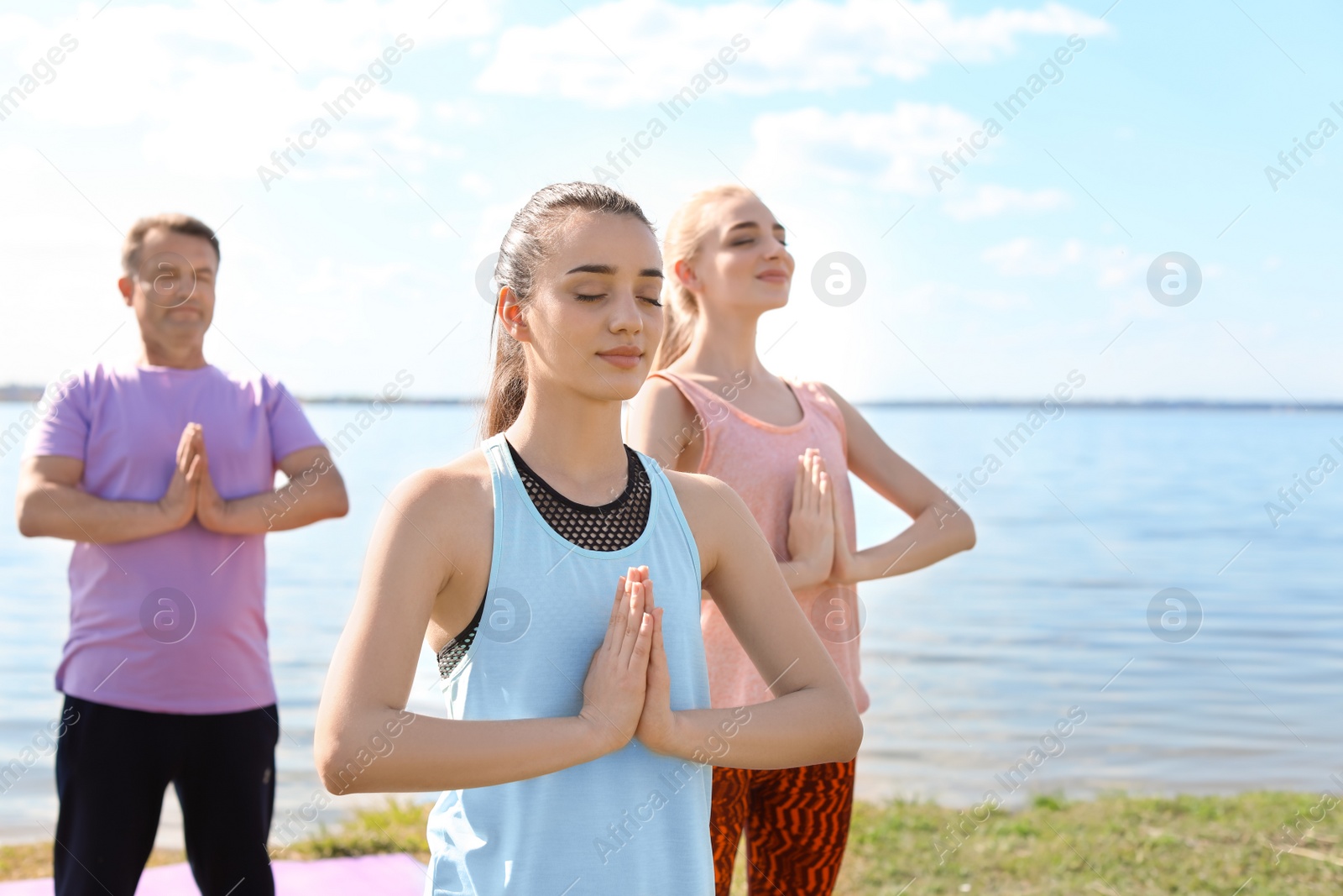 Photo of Group of people practicing yoga near river on sunny day