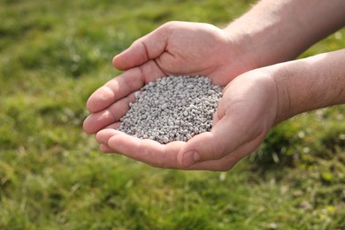 Photo of Man with fertilizer in hands outdoors, closeup