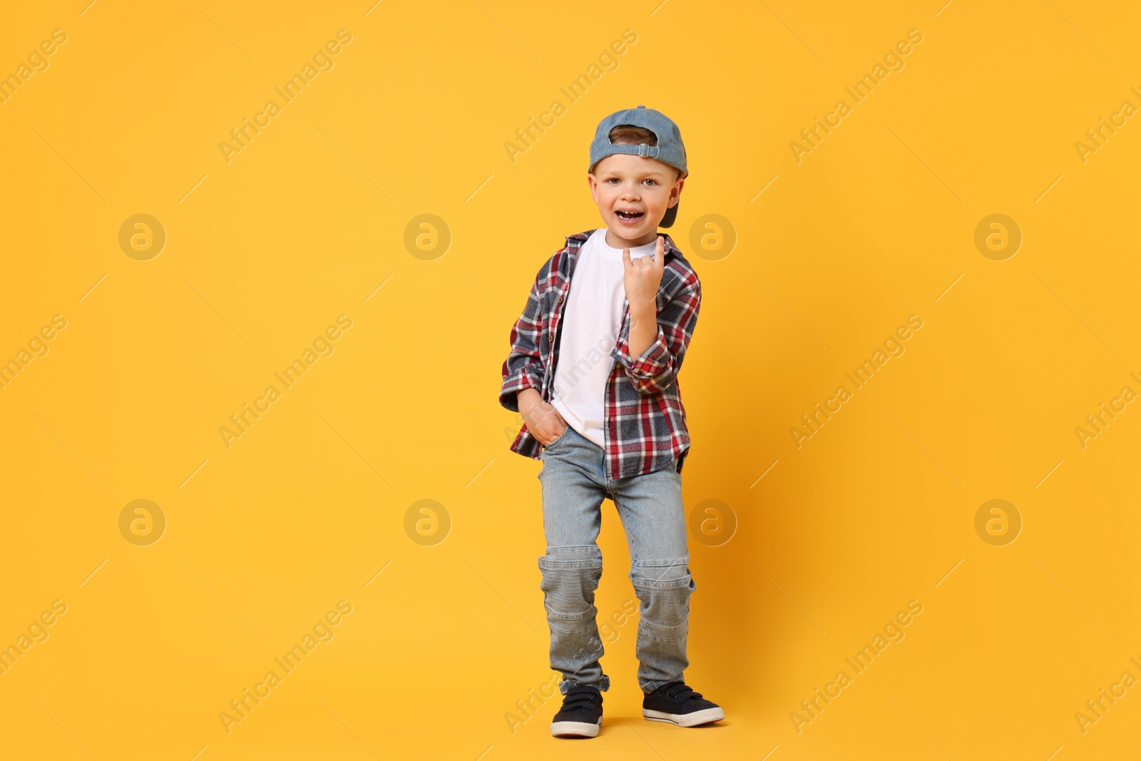 Photo of Happy little boy dancing on yellow background