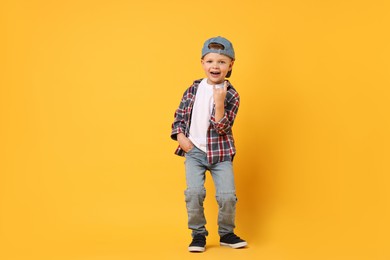 Happy little boy dancing on yellow background