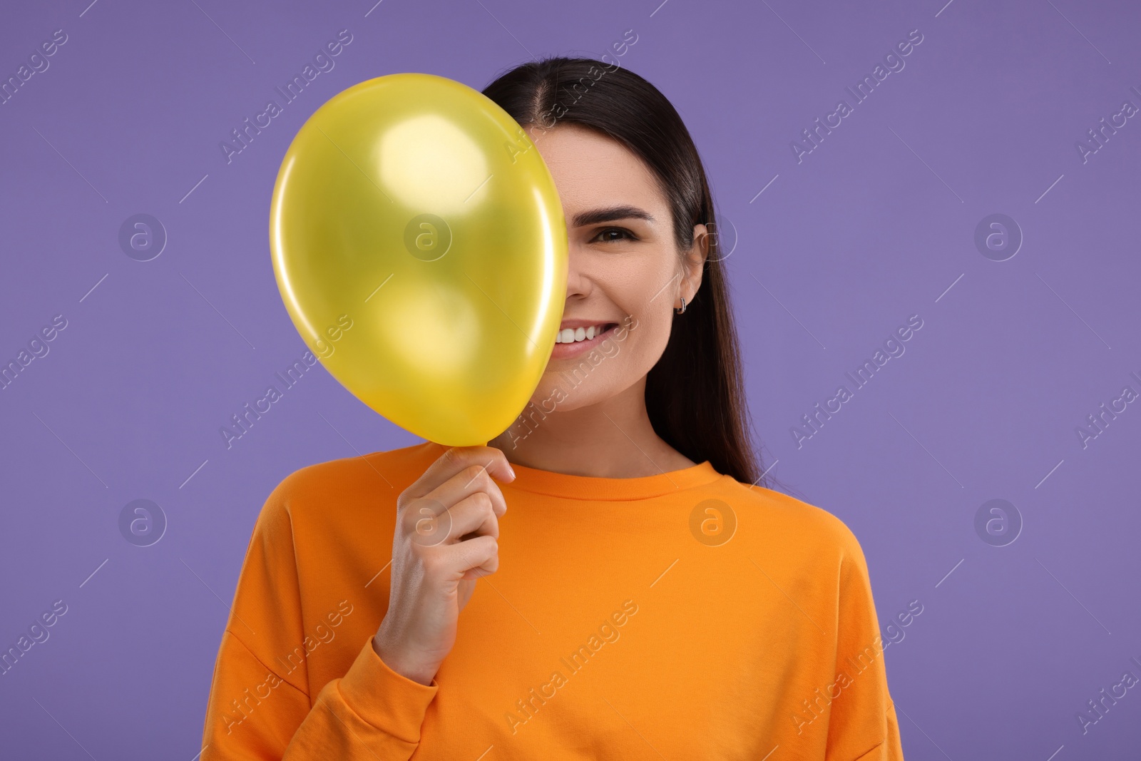 Photo of Happy woman with yellow balloon on purple background