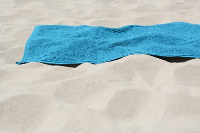 Soft blue towel on sandy beach, space for text