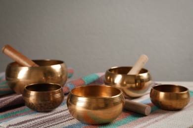 Photo of Tibetan singing bowls with mallets on colorful fabric, space for text
