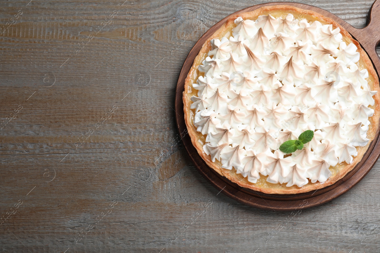 Photo of Delicious lemon meringue pie decorated with mint on wooden table, top view. Space for text