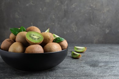 Fresh ripe kiwis in bowl on grey table, space for text
