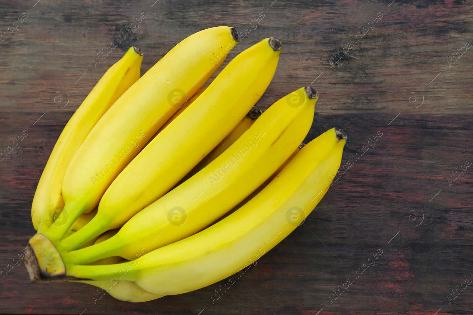 Photo of Bunch of ripe yellow bananas on wooden table, top view