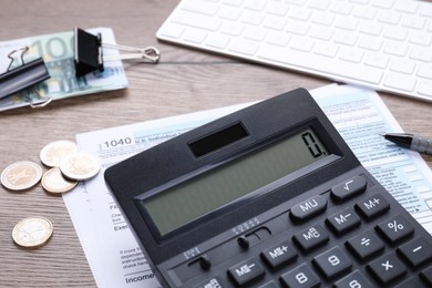 Photo of Tax accounting. Calculator, documents, money, stationery and keyboard on wooden table, closeup