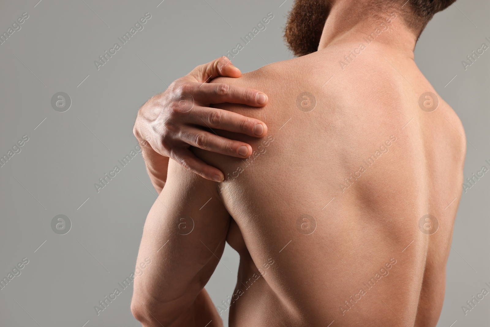 Photo of Man touching his shoulder on light grey background, closeup