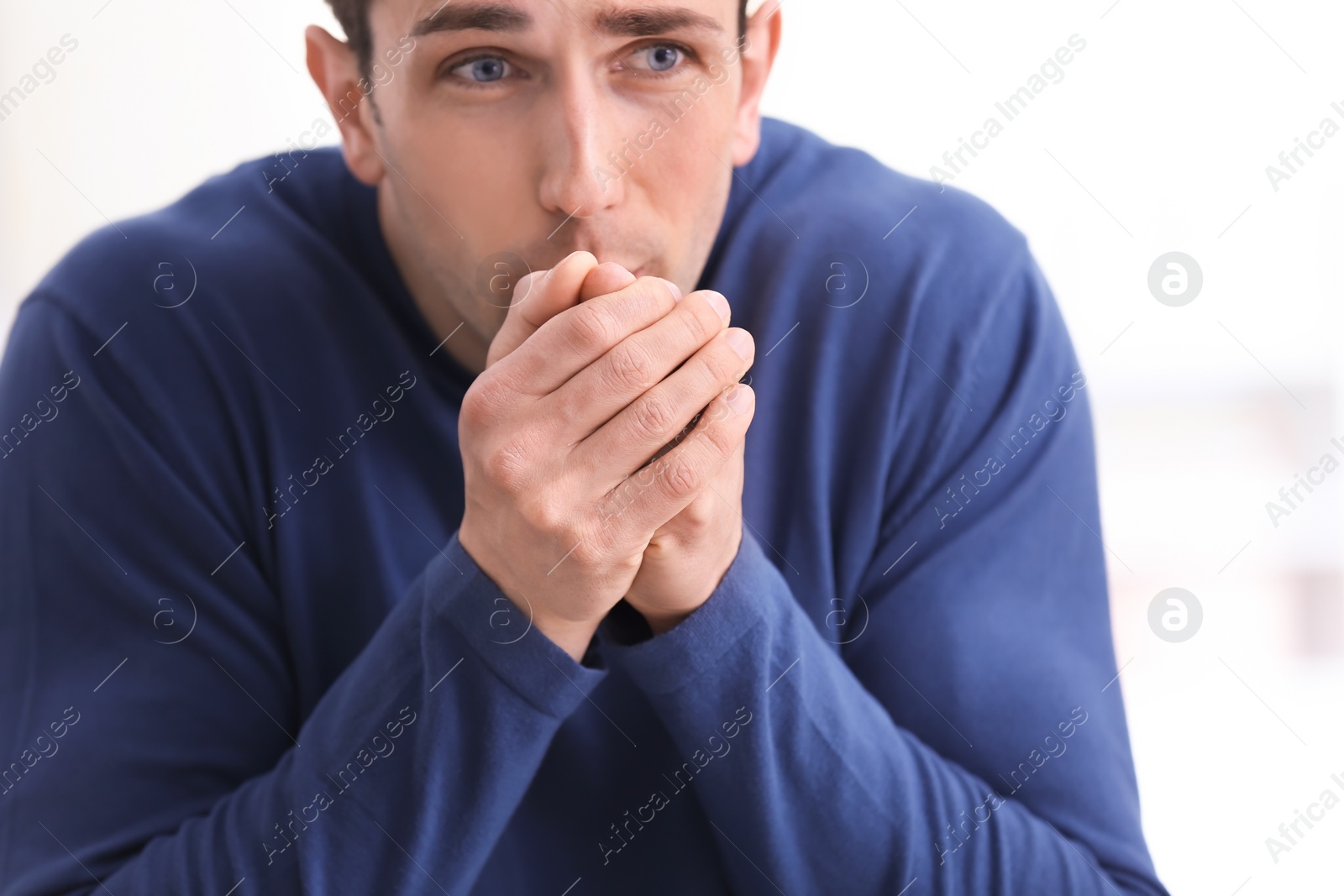 Photo of Sad young man suffering from cold on blurred background