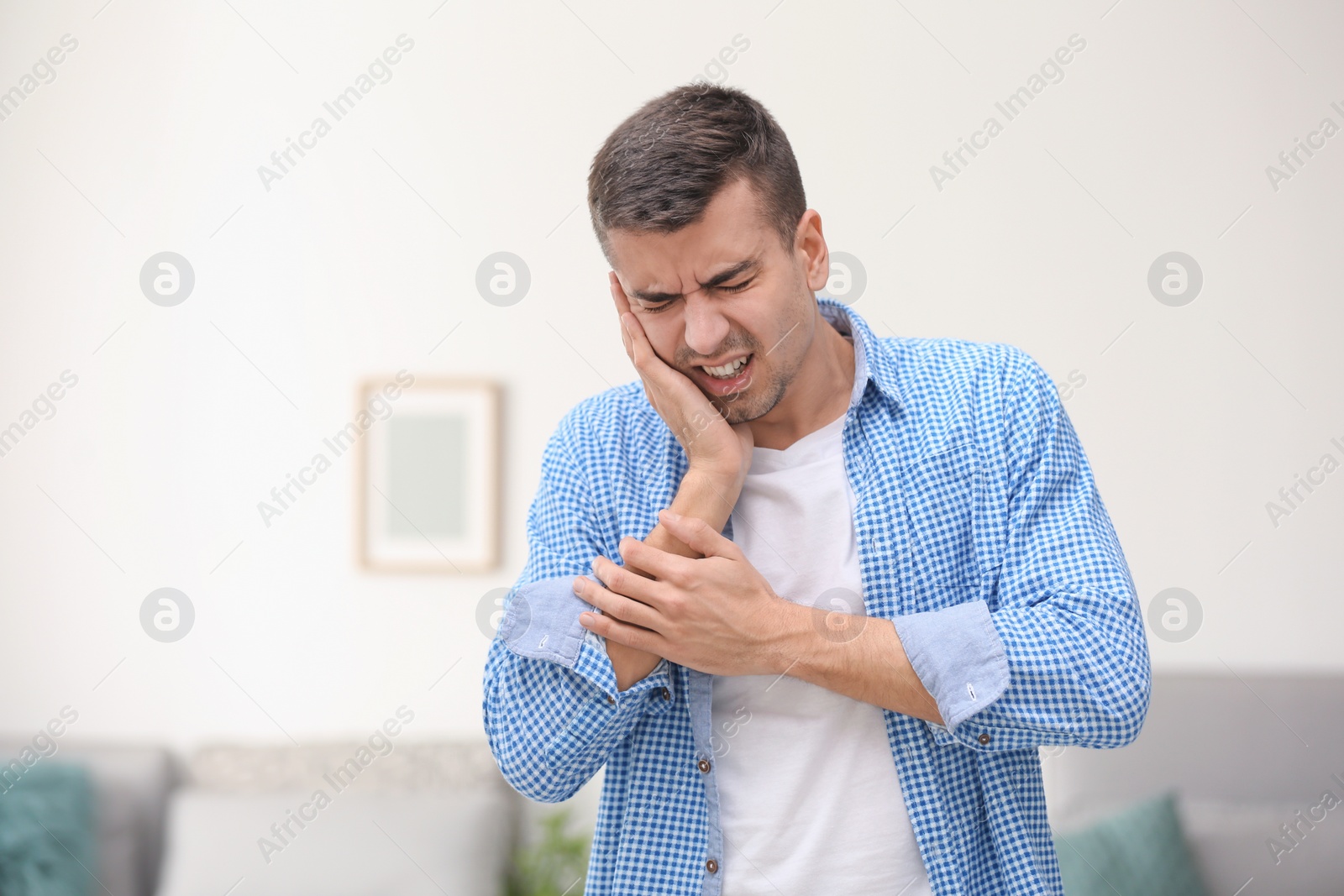 Photo of Young man suffering from toothache  at home