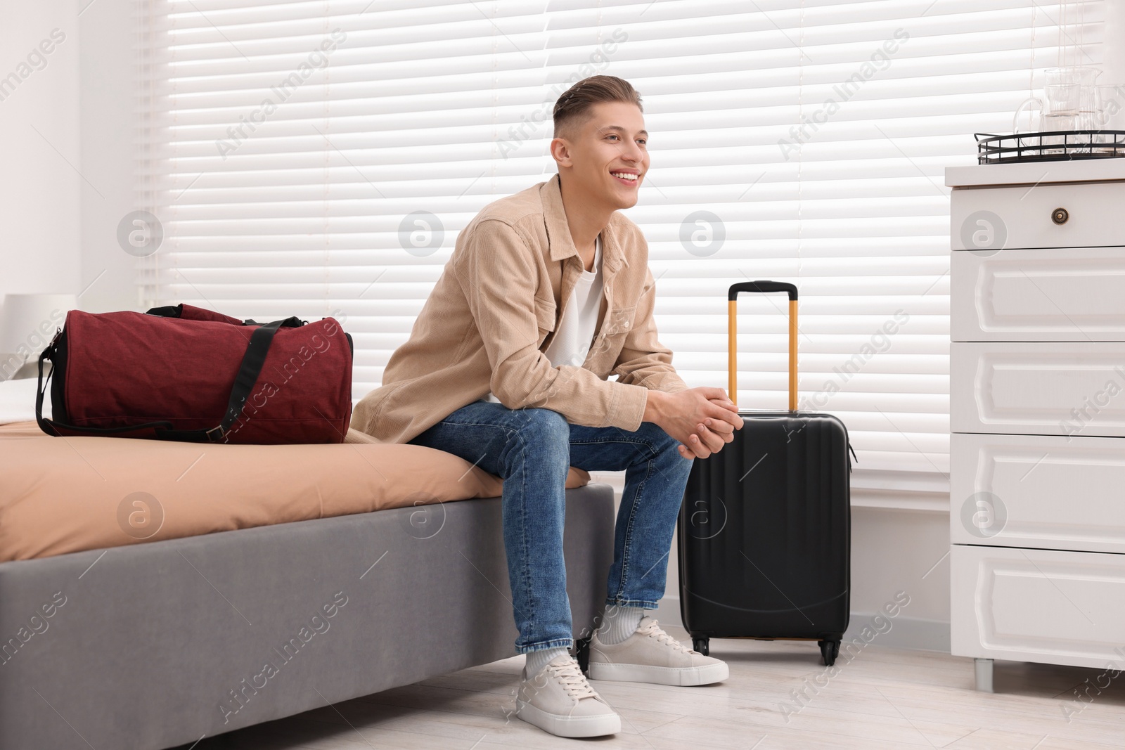 Photo of Smiling guest relaxing on bed in stylish hotel room