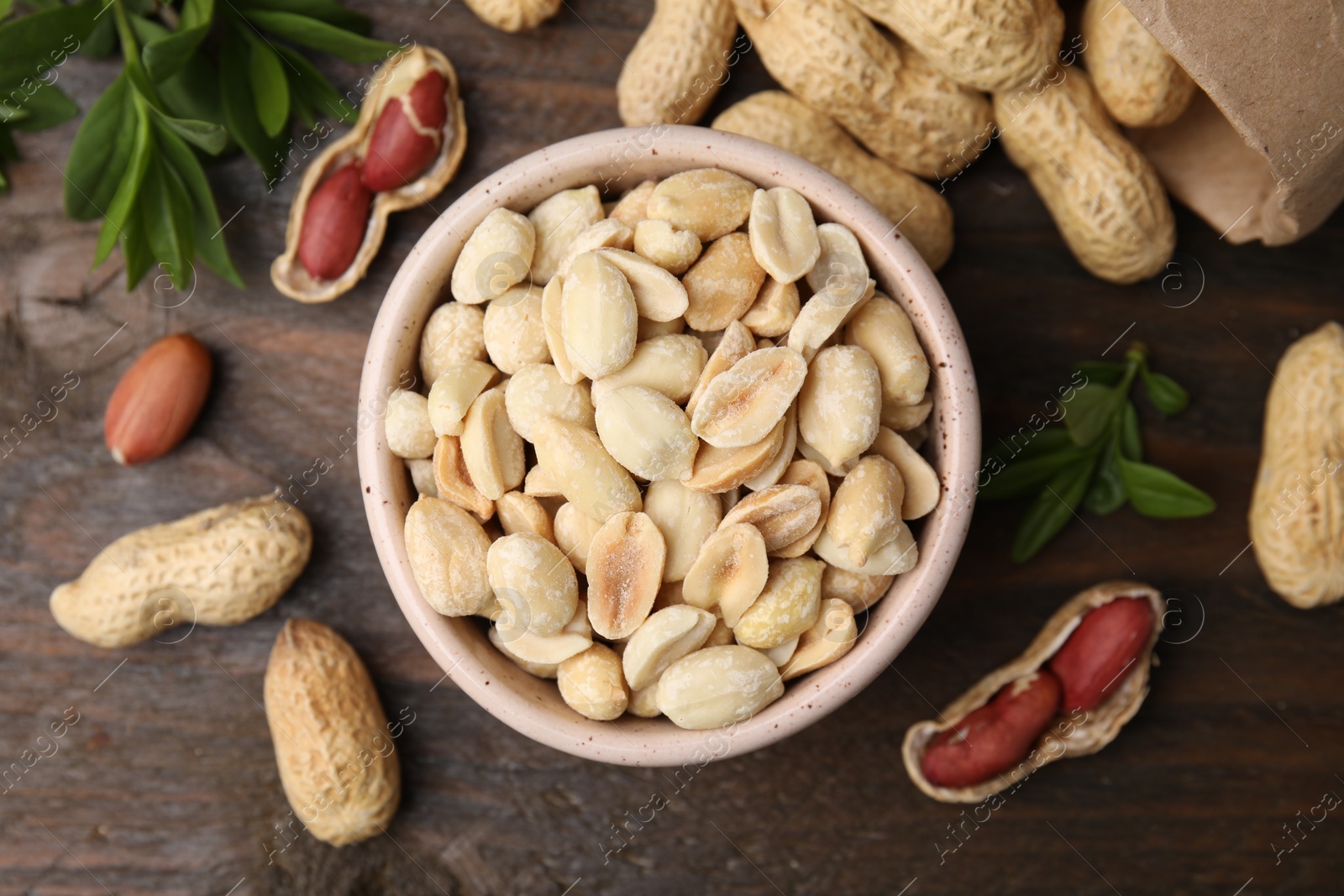 Photo of Fresh peanuts and leaves on wooden table, flat lay