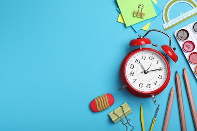 Photo of Flat lay composition with alarm clock and different stationery on light blue background, space for text. School time
