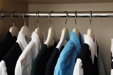 Photo of Hangers with teenage clothes on rack in wardrobe, closeup