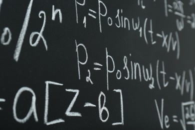 Photo of Many different math formulas written on chalkboard, closeup