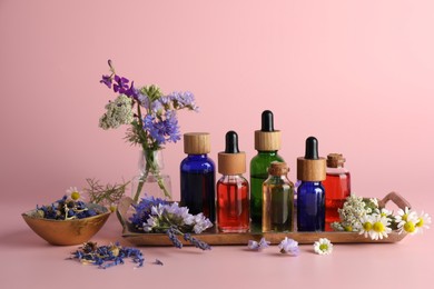 Aromatherapy. Different essential oils and flowers on pink background