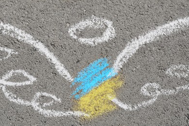 Photo of Angel drawn with colorful chalks on asphalt outdoors, closeup