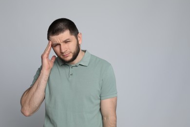 Man suffering from headache on light grey background. Space for text