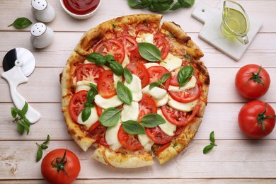 Photo of Delicious Caprese pizza with tomatoes, mozzarella and basil on light wooden table, flat lay