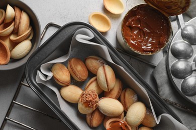 Photo of Delicious walnut shaped cookies with condensed milk on grey table, flat lay