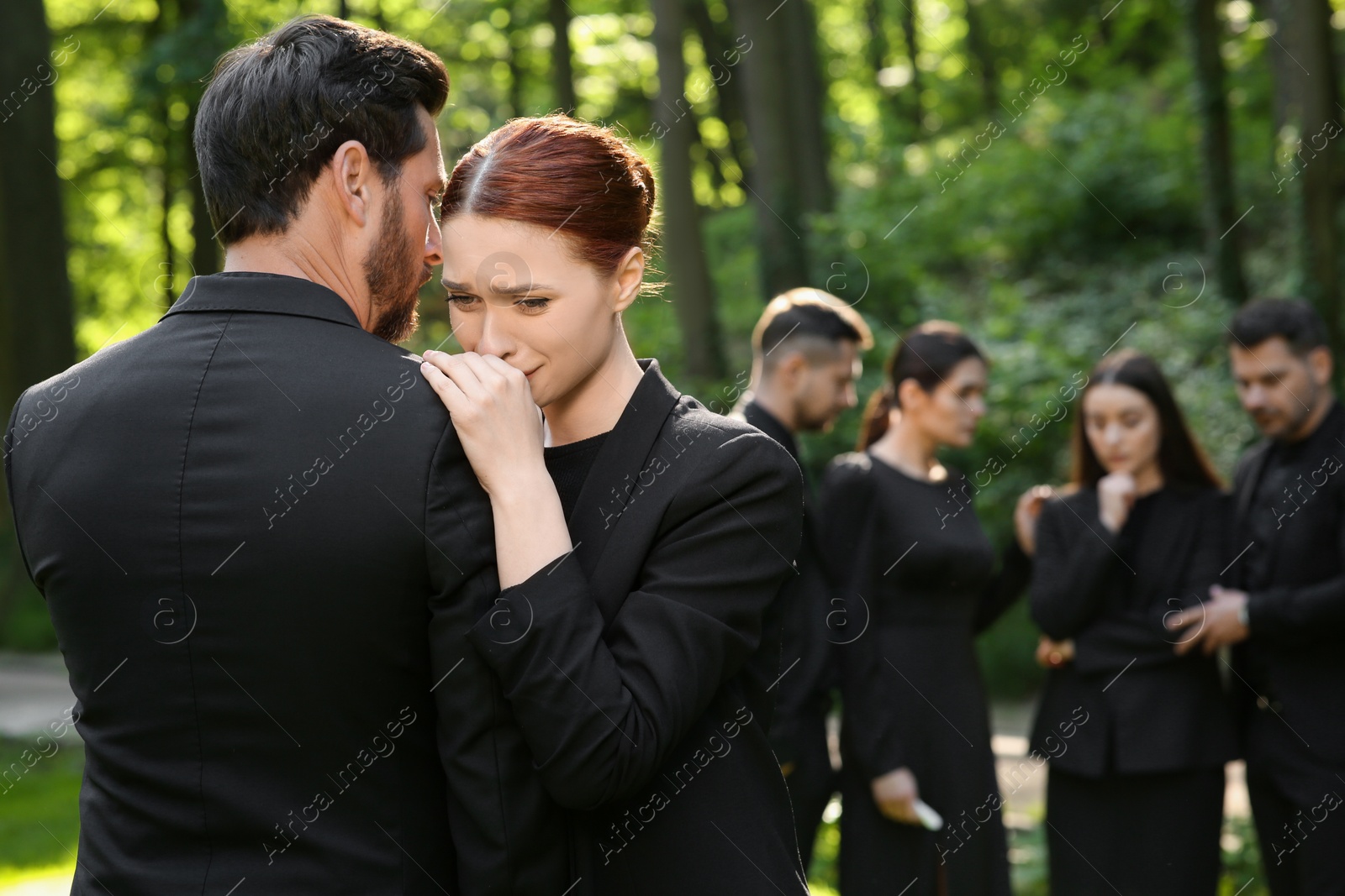 Photo of Sad people in black clothes mourning outdoors. Funeral ceremony