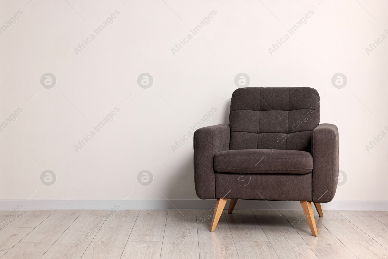 Photo of Comfortable armchair near white wall in room, space for text