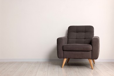 Photo of Comfortable armchair near white wall in room, space for text