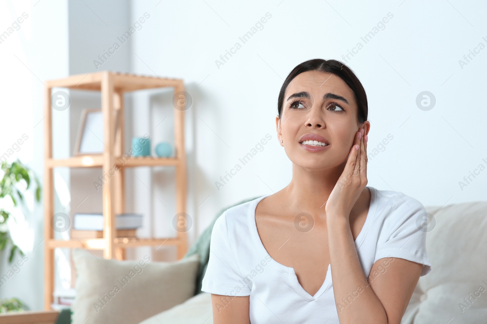 Photo of Young woman suffering from ear pain at home