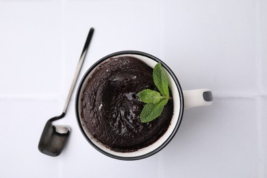 Tasty chocolate mug pie and spoon on white table, top view. Microwave cake recipe