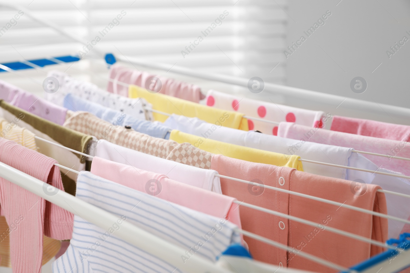 Photo of Clean laundry hanging on drying rack indoors, closeup